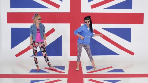 Κάμερα δείχνει πρόβα των κοριτσιών με γυαλιά ηλίου που χορεύουν σε φόντο της σημαίας του Ηνωμένου Βασιλείου — Αρχείο Βίντεο