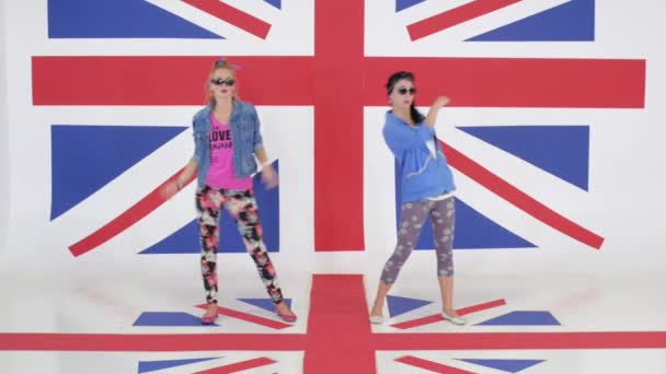 Ensaio de duas meninas muito engraçadas dançando em estúdio com papéis de parede de bandeira do Reino Unido — Vídeo de Stock