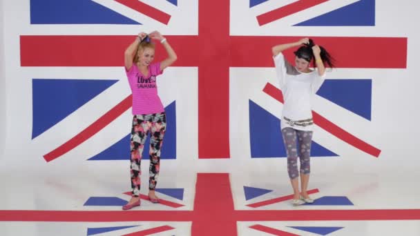 Entrenamiento de dos chicas muy divertidas bailando en el estudio con fondos de pantalla de la bandera del Reino Unido — Vídeos de Stock