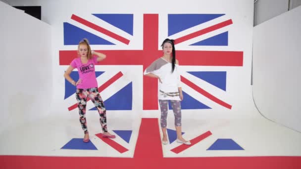 두 매력적인 웃는 여자 영국 국기의 배경에 춤 운동을 — 비디오