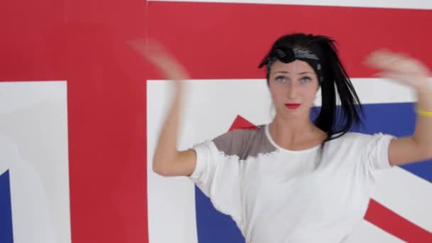 Pretty brunette female looks at camera and dances on background of british flag — Stock Video