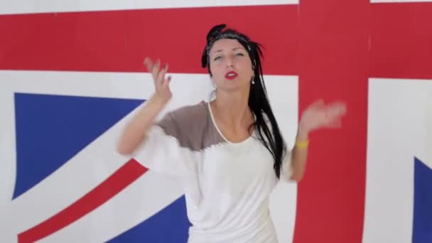 Mulher de cabelos escuros de boa aparência dança emocionalmente no fundo da bandeira do Reino Unido — Vídeo de Stock