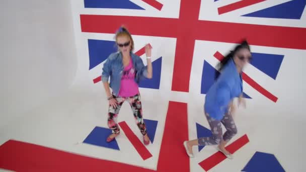 Sexy mladé ženy v taneční cvičení sluneční brýle pohybující se ve studiu s vlajkou Velké Británie — Stock video