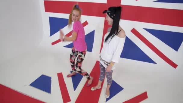 Two charismatic girls in t-shirts look at camera and synchronically dance — Stock Video