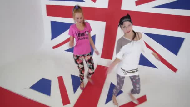 Roztomilá aktivní dívky podívat na kameru a tančit v bílých studio s velkým Uk vlajka