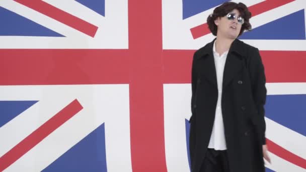 Junger Mann mit Perücke, Sonnenbrille und Mantel singt vor Kamera und Handgesten. — Stockvideo