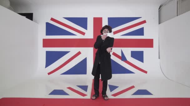 Künstler mit Perücke, Sonnenbrille, Mantel und weißem Tuch in der Hand singt im Atelier — Stockvideo