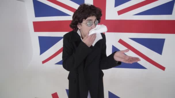 Смешной человек в парике, солнцезащитных очках и пальто вытирает лицо белой тканью и поет — стоковое видео