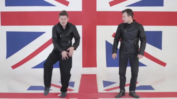 Zwei gut aussehende Männer in schwarzen Motorradjacken aus Leder tanzen synchron. — Stockvideo