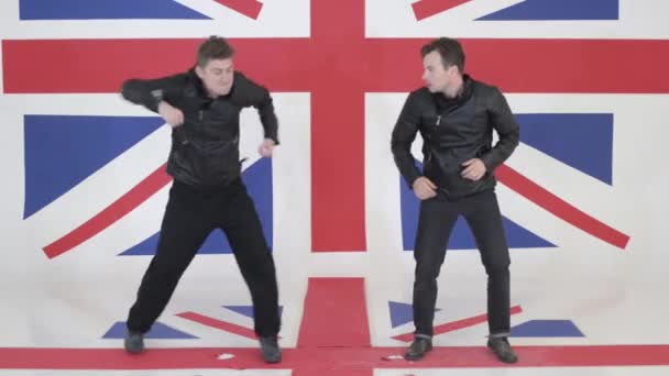 Two handsome males in black leather motorcycle jackets synchronically dance. — Stock Video