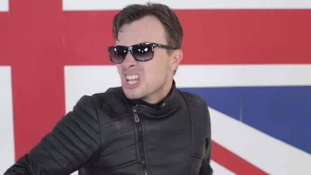 Cute guy with sunglasses in leather motorcycle jacket sings and dances on camera — Stock Video
