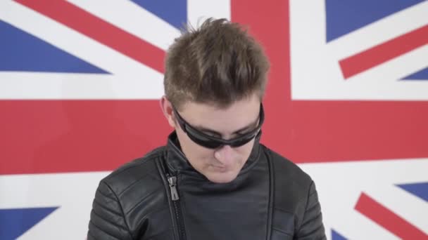 Красивый парень в солнечных очках в кожаной куртке мотоцикла позирует и танцует — стоковое видео