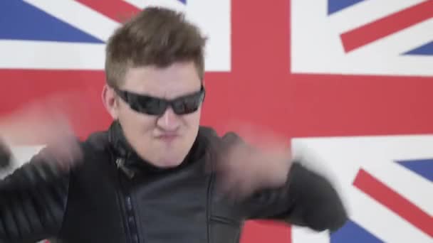 Чоловік з прохолодною стрижкою і сонцезахисними окулярами в мотоциклетній куртці співає і танцює — стокове відео