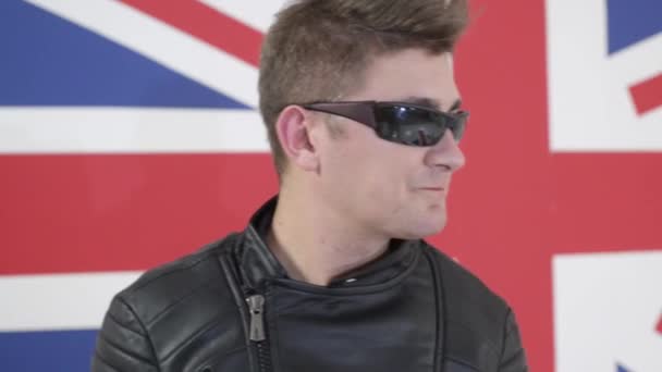 Attraktiver Mann mit modernem Haarschnitt und Sonnenbrille in Motorradjacke singt. — Stockvideo