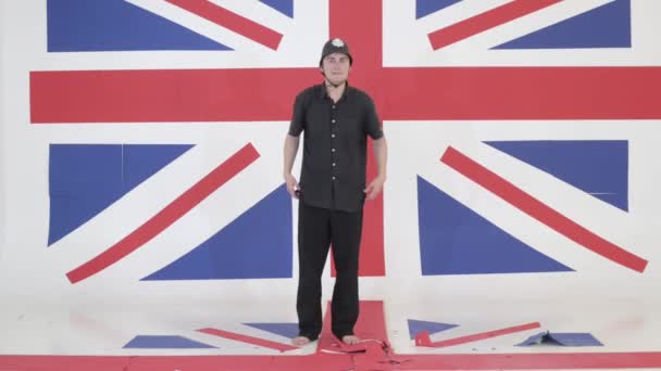 Молодой человек в защитном шлеме имитирует указчика в студии с флагом Великобритании — стоковое видео