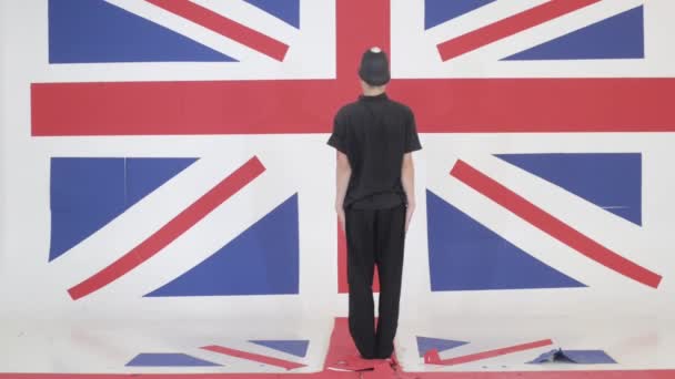 Joven hombre con casco custodio está imitando puntero en el estudio con bandera del Reino Unido — Vídeos de Stock