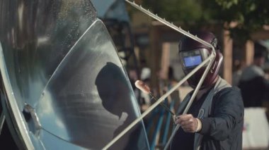 Saint Petersburg, Rusya Federasyonu - 24 Haziran 2017: Kaynakçı maskeli adam şiş sosis ile konsantre güneş ışını koyar.