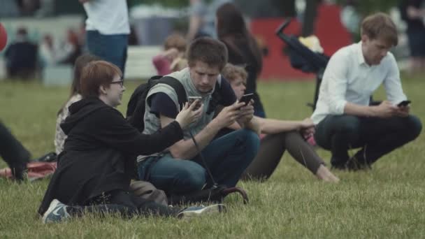 SAINT PETERSBURG, RÚSSIA - JUNHO 24, 2017: Menina mostrando fotos de homem na tela do telefone inteligente e rindo do parque da cidade — Vídeo de Stock