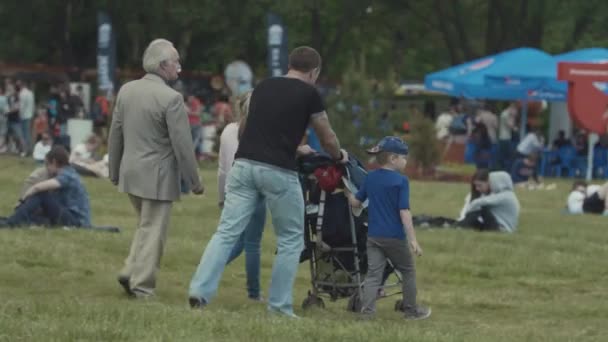 Saint petersburg, russland - 24. juni 2017: familienvater schiebt kinderwagen mit kindern auf rasen im stadtpark — Stockvideo