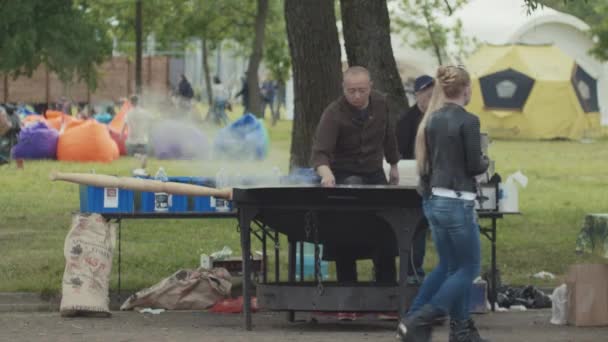 САЙНТ-ПЕТЕРБУРГ, РОССИЯ - 24 июня 2017 года: Азиатская уличная кухня быстрого питания в городском парке, большой дымящийся металлический котел — стоковое видео