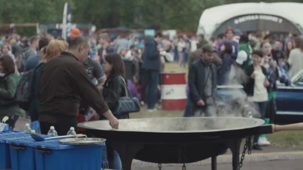 САЙНТ-ПЕТЕРБУРГ, РОССИЯ - 24 июня 2017 года: Азиатский уличный повар смешивает в большой миске вок на переполненном фестивале городского парка — стоковое видео