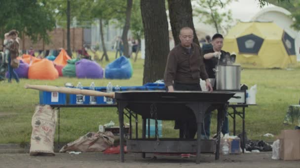 SAN PETERSBURG, RUSIA - 24 DE JUNIO DE 2017: Puesto de comida rápida en la calle asiática en el parque de la ciudad, gran wok de metal humeante — Vídeo de stock