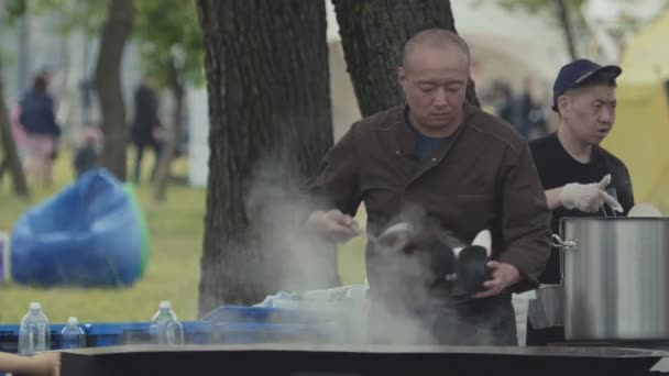 SAN PETERSBURG, RUSIA - 24 DE JUNIO DE 2017: Contador de comida rápida en la calle asiática en el parque de la ciudad, gran wok de metal humeante — Vídeo de stock