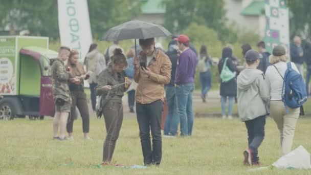 Saint Petersburg, Federacja Rosyjska - 24 czerwca 2017: Para pod parasolem na trawniku zatłoczone miasta park summer Festival — Wideo stockowe