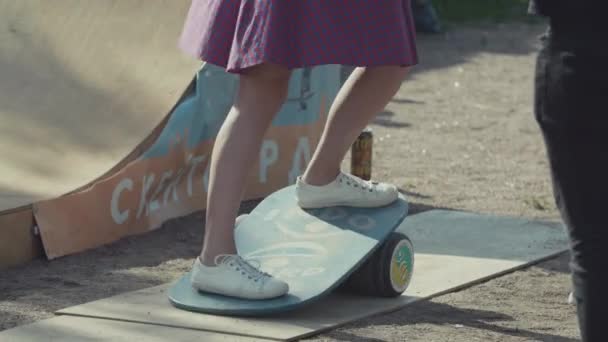САЙНТ-ПЕТЕРБУРГ, РОССИЯ - 24 июня 2017 года: Девушка-подросток пытается встать на доску для равновесия в скейт-парке — стоковое видео