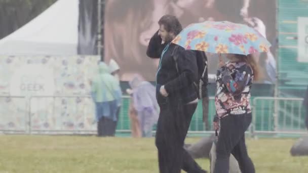 SAINT PETERSBURG, RUSSIA - JUNE 24, 2017: Couple walking in pouring rain, woman with umbrella, man caress wet hair — Stock Video