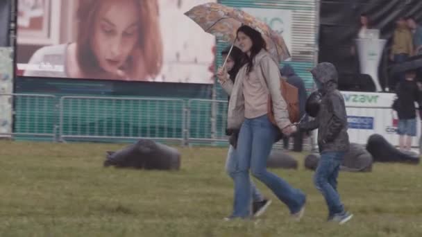 SAINT PETERSBURG, RUSSIA - 24 GIUGNO 2017: Madre con bambini cammina sul prato erboso sotto la pioggia al festival estivo del parco cittadino — Video Stock