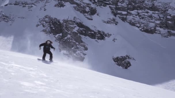 Χιονοδρομικό κέντρο. Snowboarder βόλτα στην πλαγιά. Σπρέι χιονιού. Χειραψία. Ηλιόλουστη μέρα — Αρχείο Βίντεο