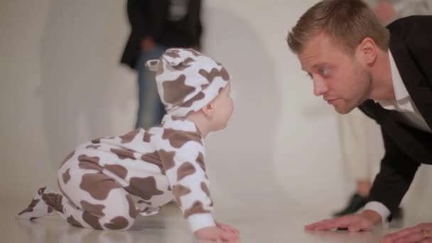 Çekici bir genç adam bebekle yerde insanlar dans arka plan üzerinde çalış — Stok video