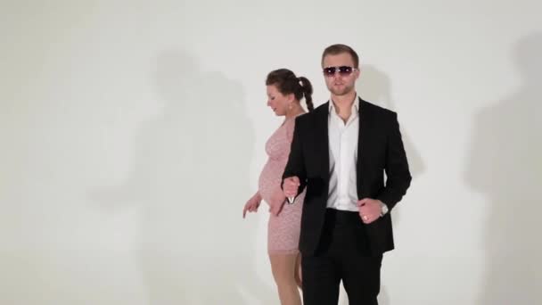 Привлекательный парень в костюме в рубашке и беременная женщина переезжают в светлую комнату — стоковое видео