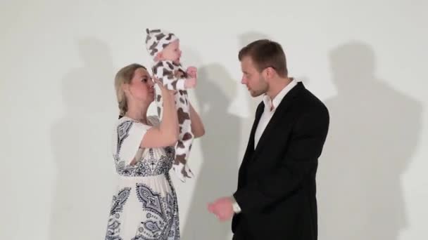 Cute blue-eyed guy in suit stands next to woman who is holding baby in hands. — Stock Video