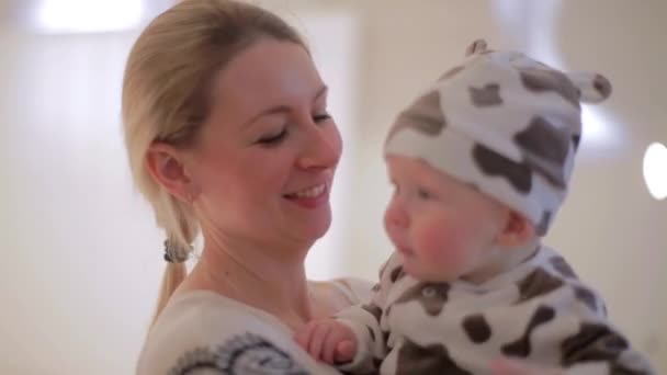 Милая белая женщина держит ребенка в руках и смотрит в камеру с улыбкой . — стоковое видео