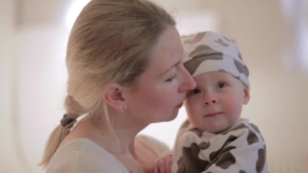 Mulher branca bonito está segurando o bebê nas mãos e beijando-o com o rosto feliz — Vídeo de Stock