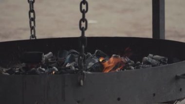 Büyük düz siyah brazier tarafından gri kül kaplı kömürleri yanan parçaları yer.