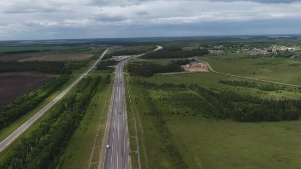 Вид на небо длинной широкой дороги с верховой ездой автомобилей, зеленые поля сельской местности — стоковое видео