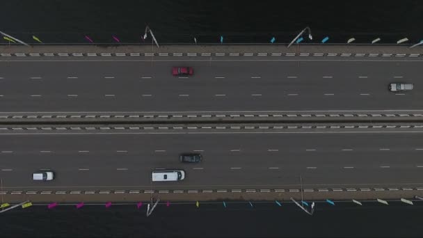 Drone met camera toont brede brug weg met veel rijden auto's op het over donkere rivier. — Stockvideo
