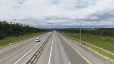 Güzel bir otomobil, kırsal alanın büyük yeşil alanları ile uzun geniş yol manzarası gökyüzü