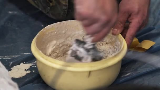 Manliga arbetstagare händer blandar vit substans i gul skål med spatel. — Stockvideo