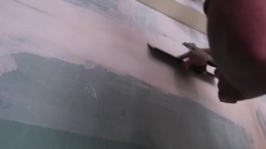 Erkek işçiler ellerini doğru gri duvar büyük spackle bıçakla alçı.