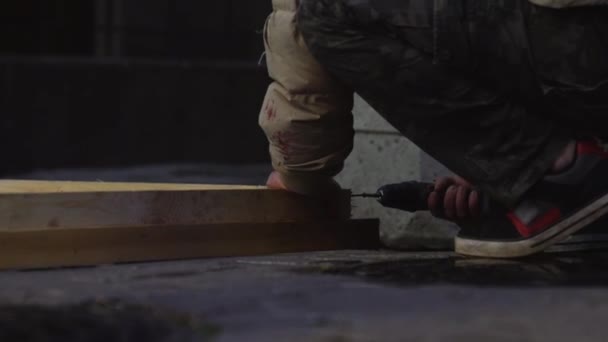 Mans hands in grey jacket are using electronic screw driver to connect planks — Stock Video