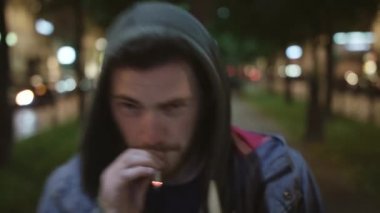 Genç Sevimli sakallı beyaz adam hoodie içinde giyinmiş içiyor ve kameraya benziyor