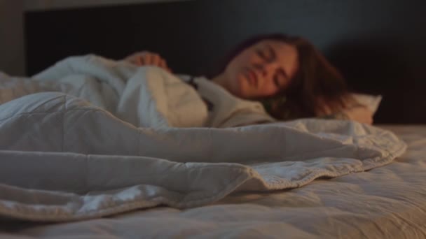 Bella donna dorme in camera da letto con la luce accesa poi improvvisamente si sveglia e sorride — Video Stock