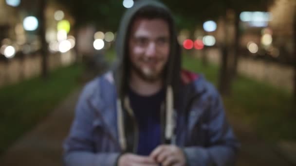 Frumos barbă caucazian om îmbrăcat în hoodie fumează și se uită la aparat de fotografiat — Videoclip de stoc