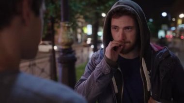 Drunk man in blouser grabs cigarette out of mouth of man in hoody and gets punch