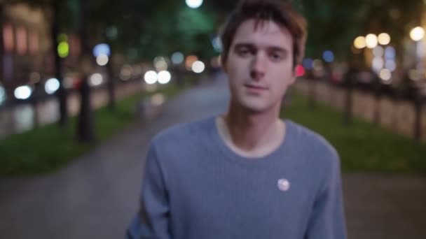 Hombre borracho en suéter sostiene la botella y camina en la calle, se acerca a la cámara — Vídeos de Stock