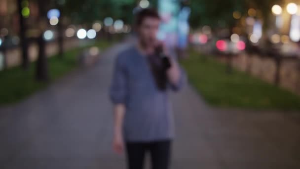 Borracho chico en blouser celebración botella camina en la calle, se acerca a la cámara — Vídeos de Stock